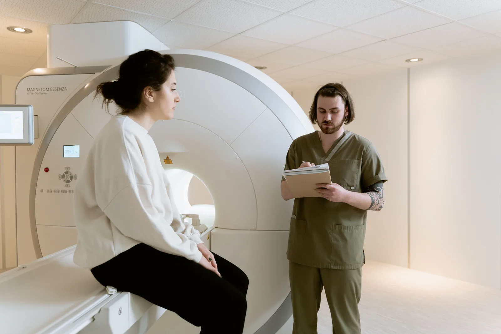 Patient speaking with an imaging technologist beside a medical scanner
