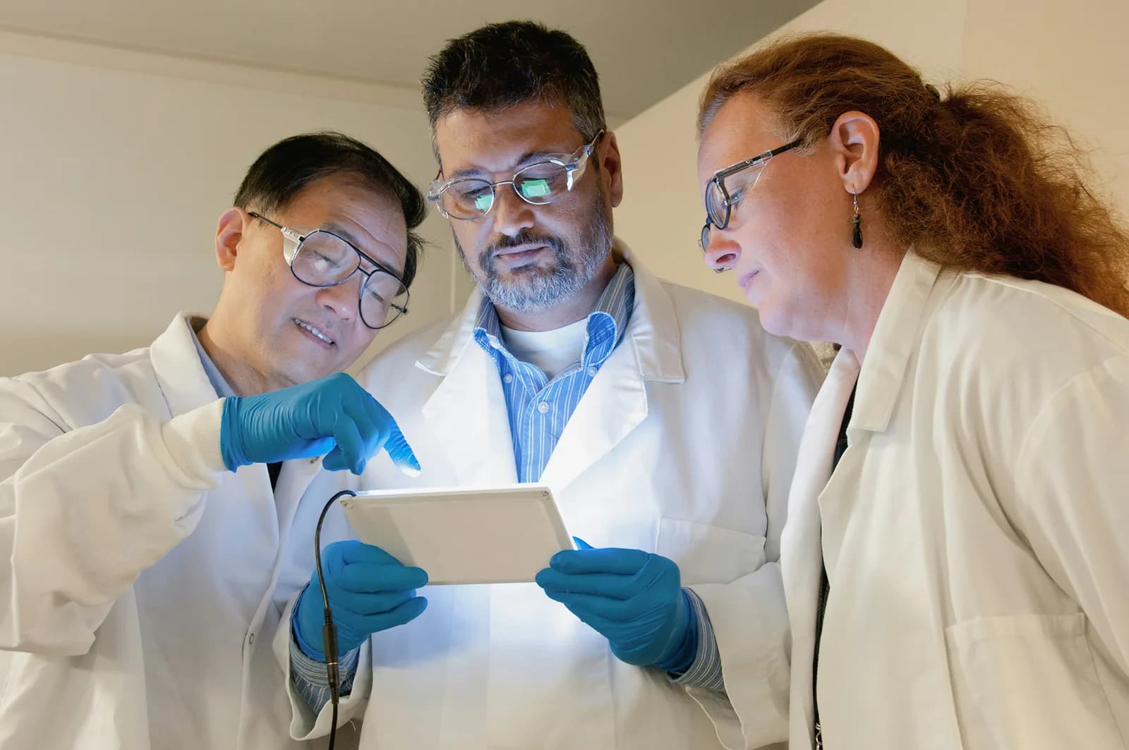 Three medical researchers reviewing information on a tablet