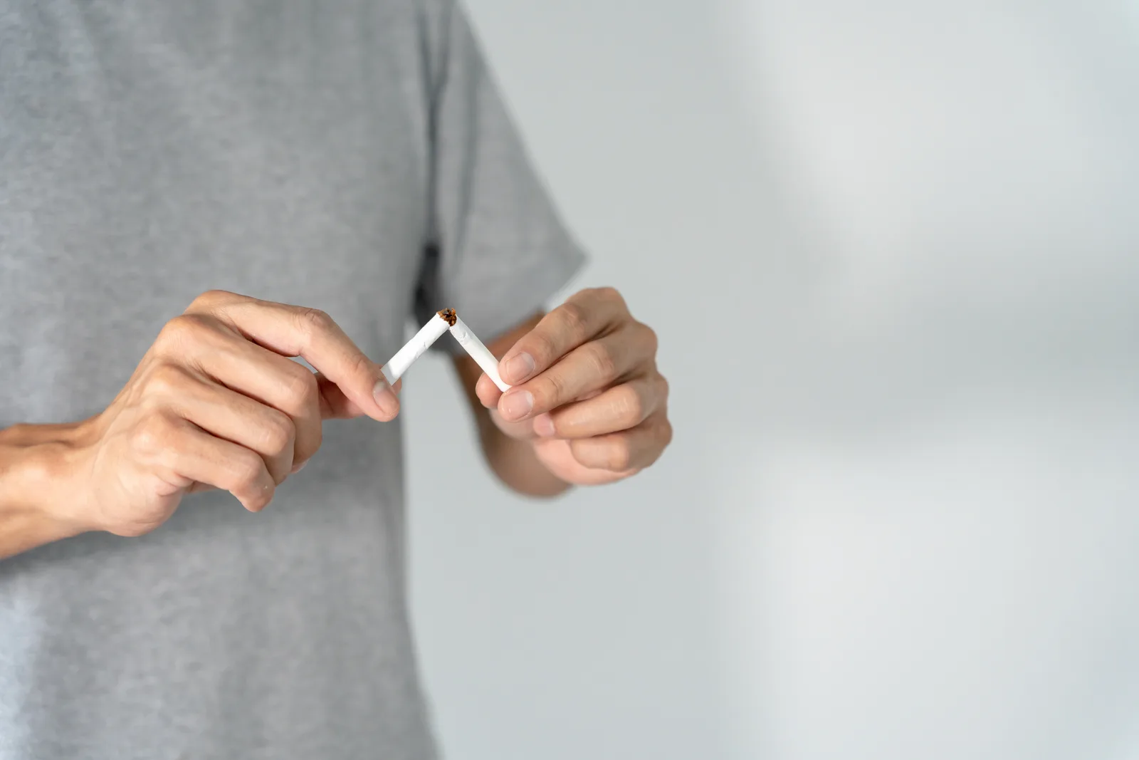 Hands breaking a cigarette in half