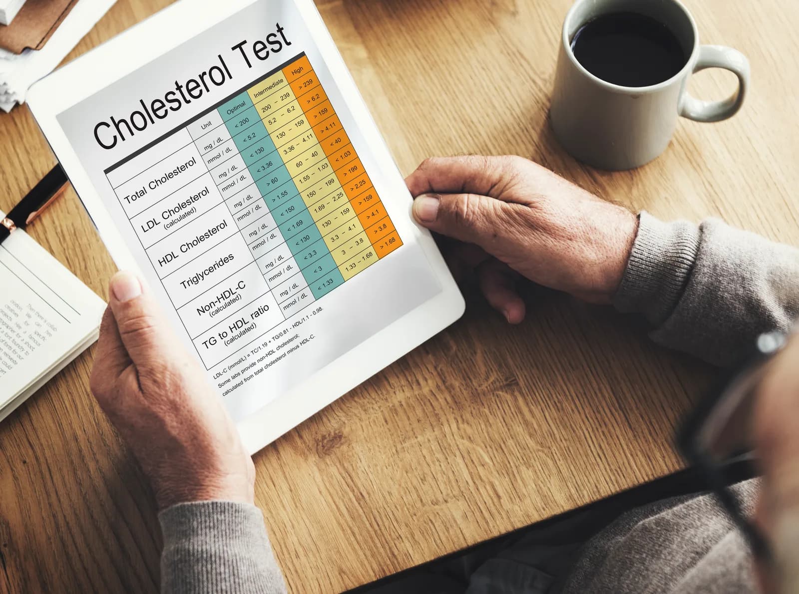 Person viewing a cholesterol test chart on a tablet at a wooden table