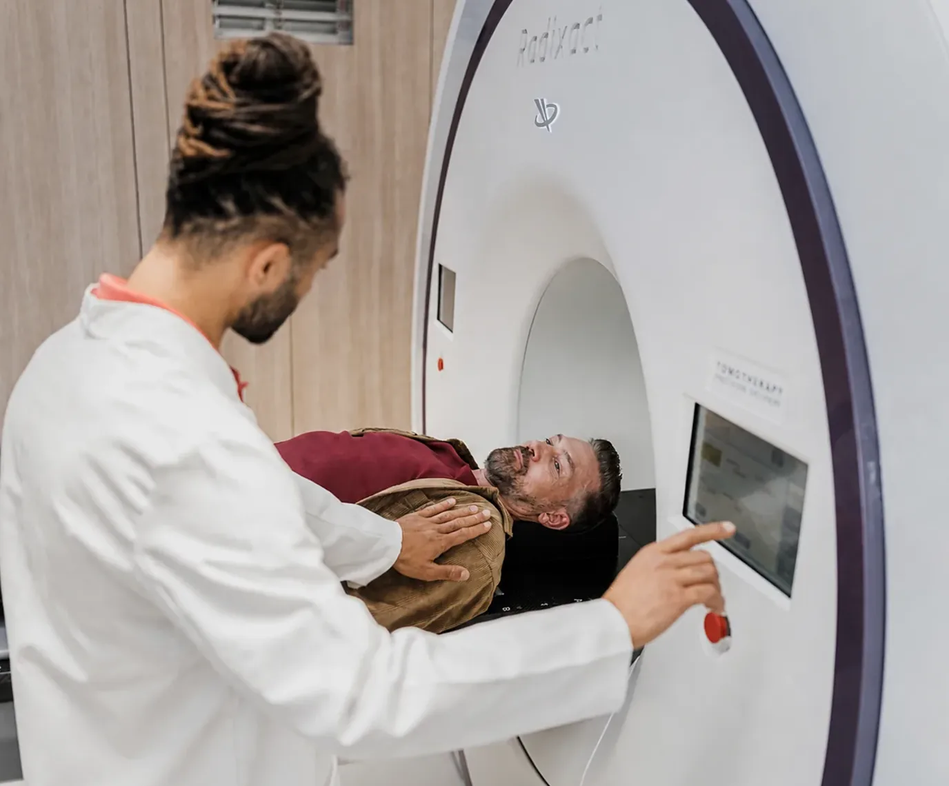Technician helping a man lie down on a scanner table