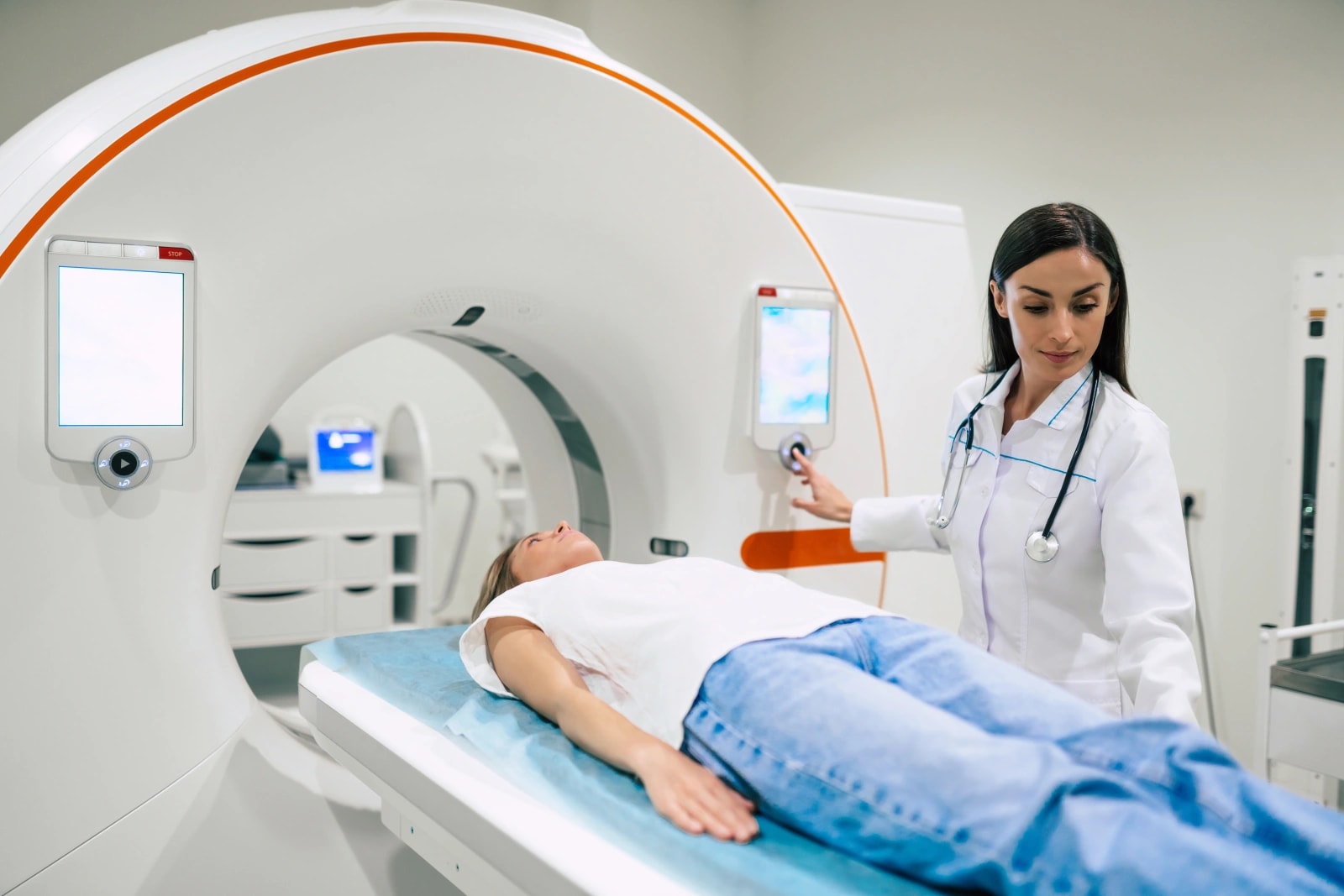 Clinician starting a CT scan for a patient lying on the scanner table