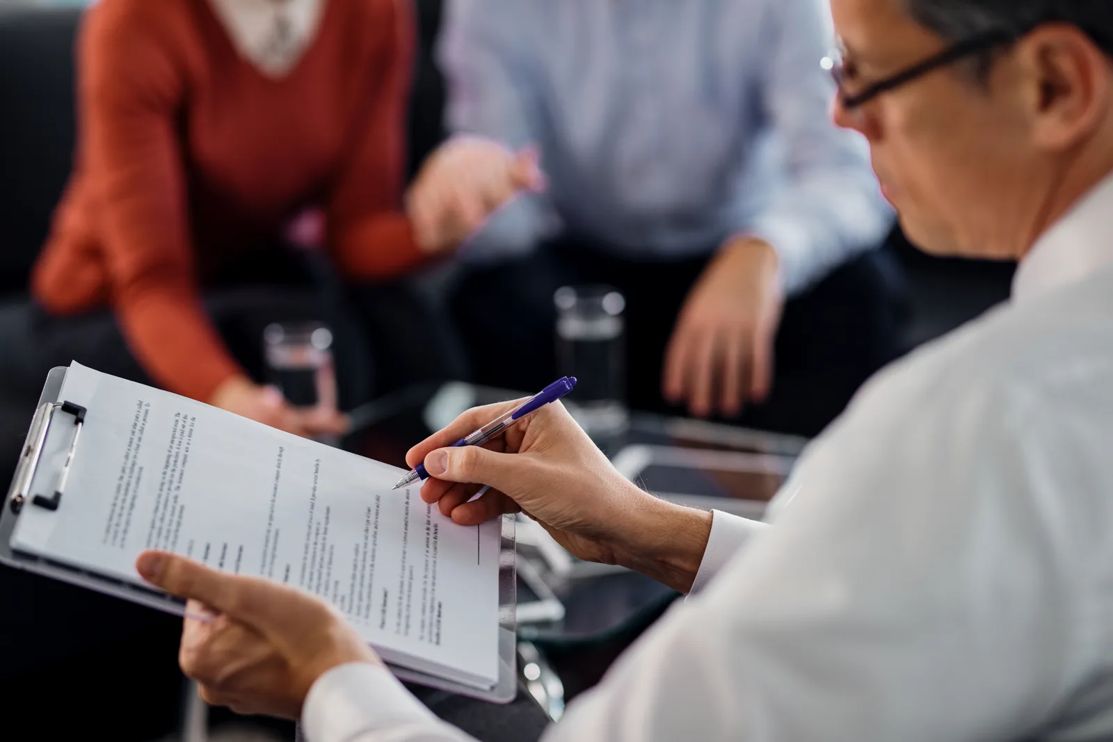 Person reviewing paperwork on a clipboard during a meeting
