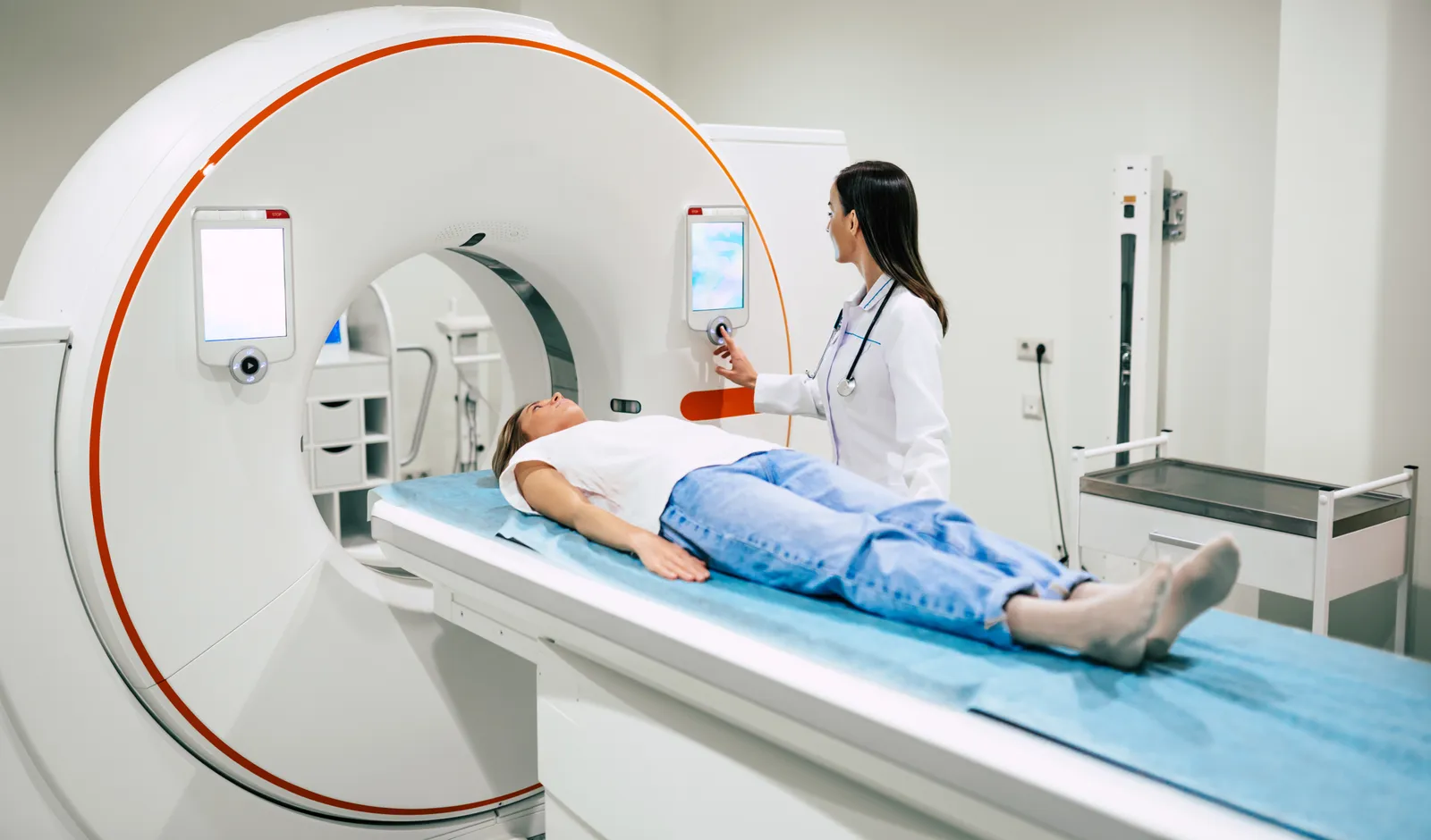 Patient lying on a CT scanner table as a clinician prepares the scan
