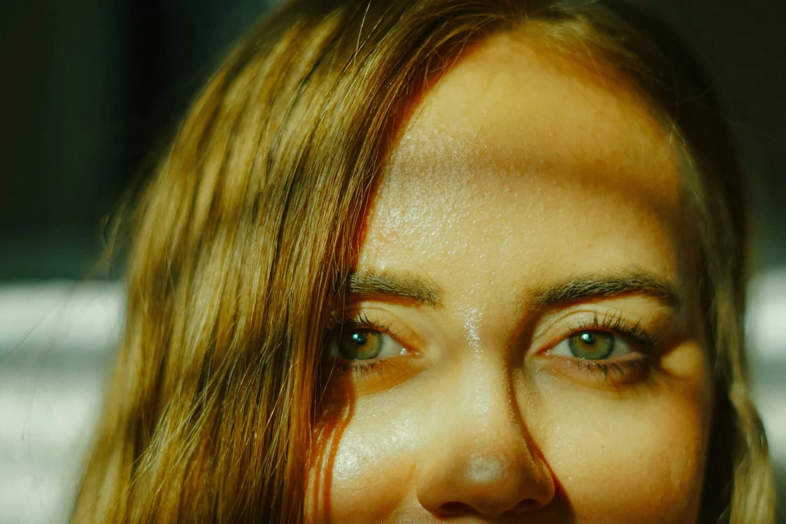 Close-up portrait of a woman with sunlight and shadows across her face