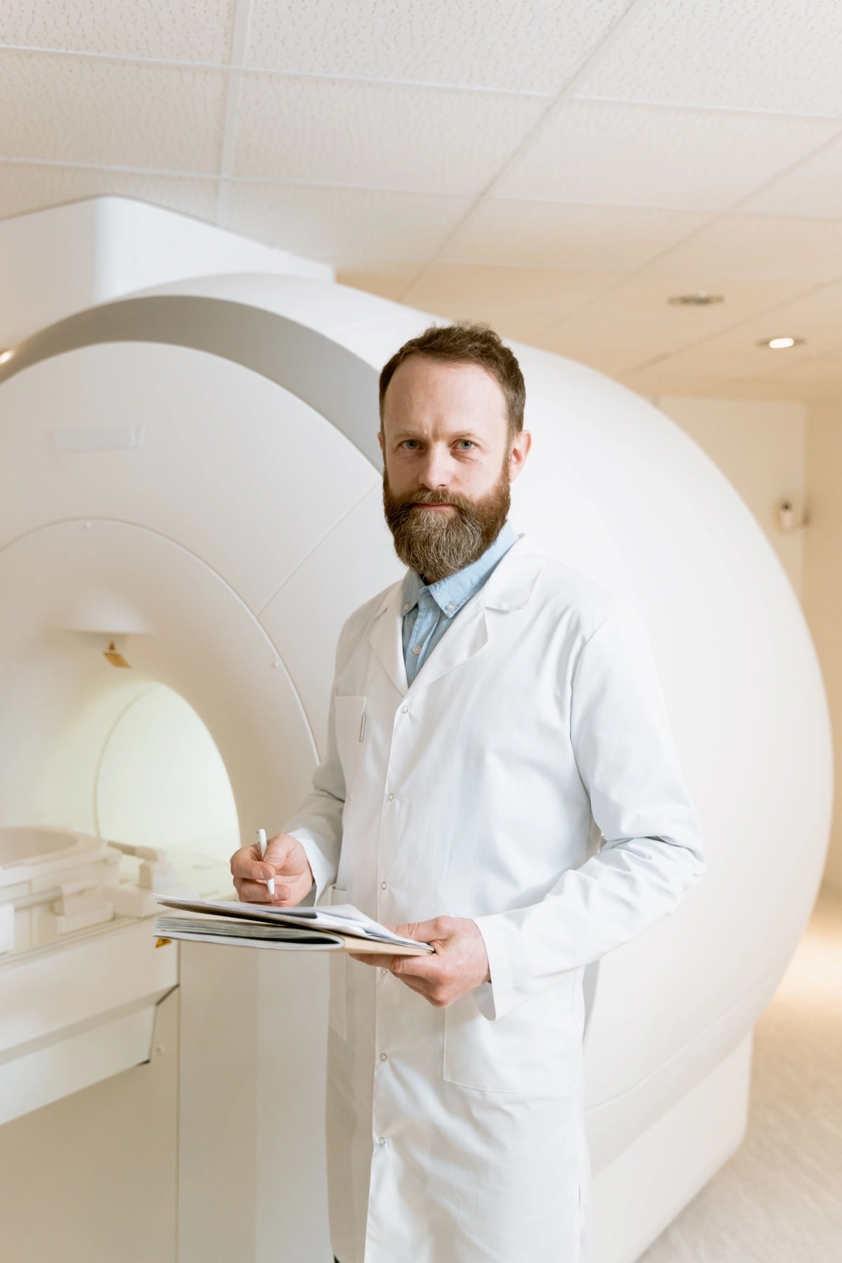 Doctor holding a clipboard beside a scanner